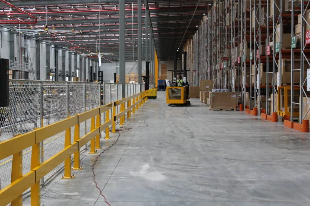 Yellow safety barriers protecting racking in a warehouse aisle