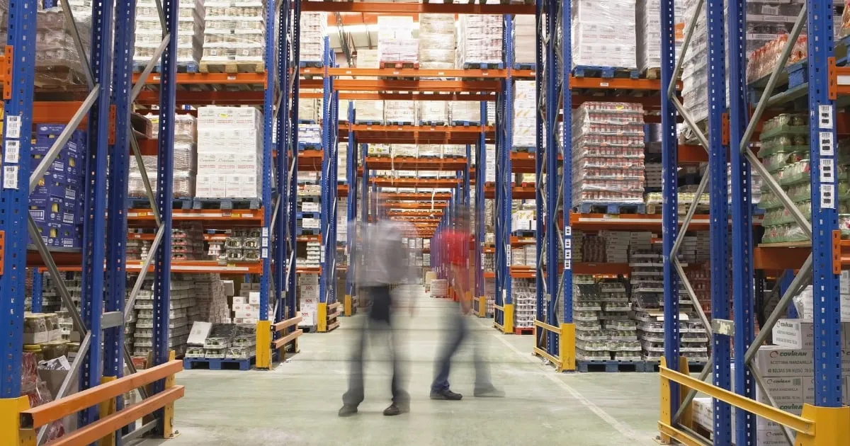 Workers walking through large warehouse storage aisles