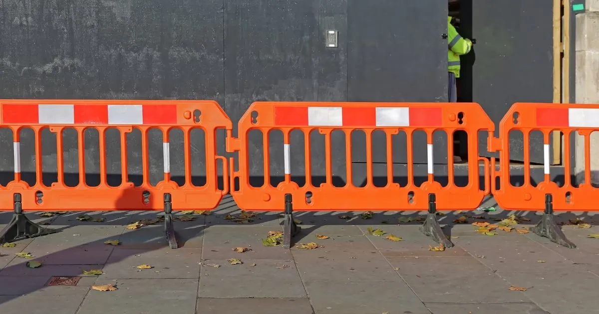 Orange safety barriers blocking pavement outside building