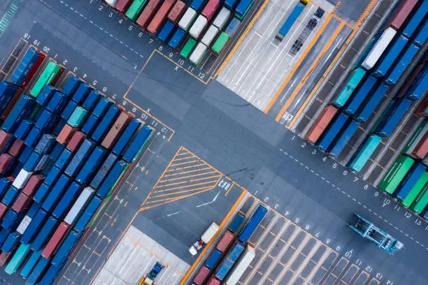 An overhead, bird's-eye view of a bustling container terminal, showing organised rows of colourful shipping containers