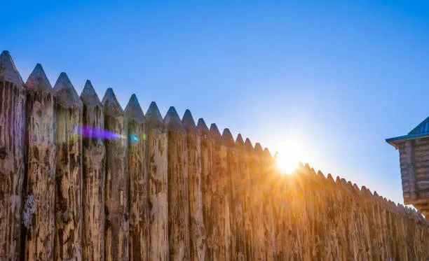 Sun setting behind wooden palisade fence