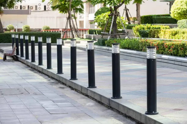 Row of black bollard lights along paved walkway