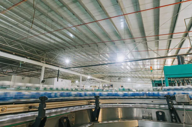 A fast-moving conveyor line carrying rows of blue and white bottles