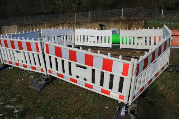 White and red construction barriers around excavation site