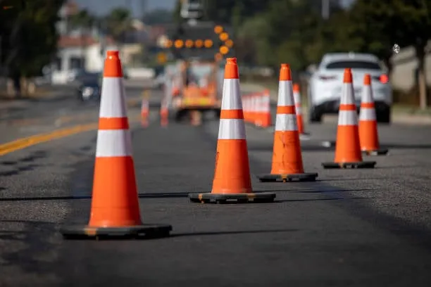 A row of orange and white reflective traffic cones diverting traffic on a paved road