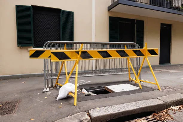Road barricade over open manhole on footpath