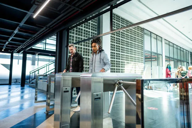 Two workers entering modern office through turnstiles