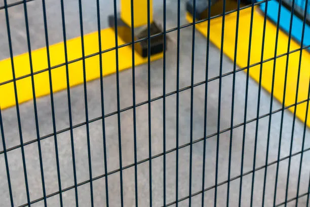 A close-up view of a black wire mesh safety fence installed in an industrial setting