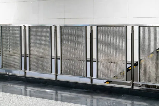 A modern stainless steel safety railing with perforated metal panels installed along a hallway