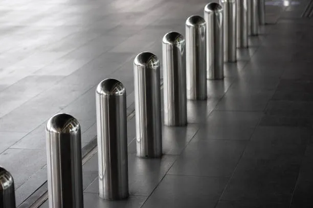 A row of polished stainless steel bollards with rounded tops